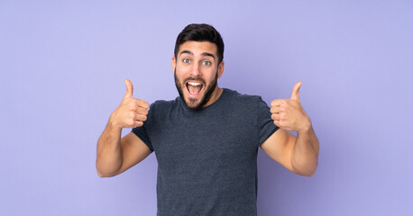 Caucasian handsome man giving a thumbs up gesture over isolated purple background