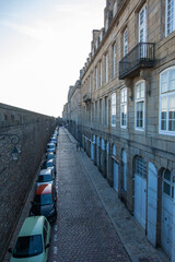 Saint-Malo, France - August 25, 2019: Historic wall and narrow street with parked cars in Intra Muros of the old town of Saint Malo, Brittany, France