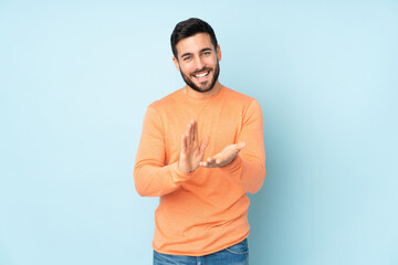 Caucasian handsome man applauding after presentation in a conference over isolated blue background