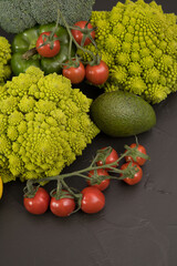 fresh vegetable, romanesco broccoli, pepper, zucchini, lemon and avocado, free space in your text, on a black table