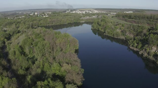 Big lake with freen trees landscape near the small town. Drone air view.