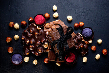 Chocolate candy truffle with chocolate pieces and flying cocoa powder on a dark background