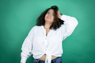 Young african american girl wearing white shirt over green background putting one hand on her head...