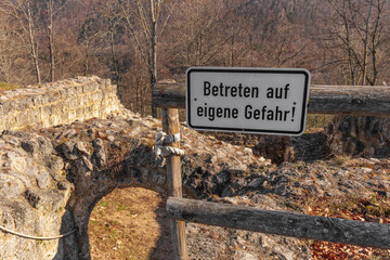 Warning sign "Enter at your own risk!"  in German,  against the background of ruins