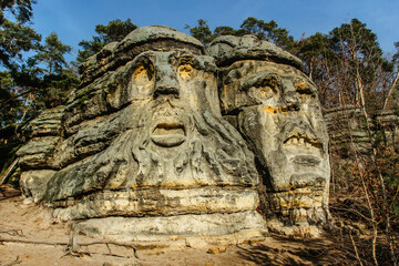 Fototapeta premium Two giant heads of devils carved into sandstone rocks,each is about 9m high.Devils Heads created by Vaclav Levy near Libechov, Czech republic.Cliff carvings carved in pine forest.Tourist attraction.