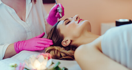 Obraz na płótnie Canvas Cosmetologist giving woman a skin treatment with laser technology