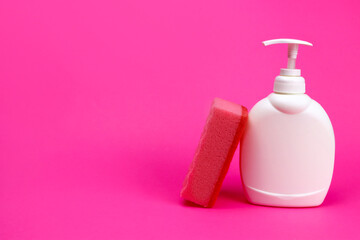 sponge and bottle of detergent on a pink background, the concept of cleaning, washing dishes