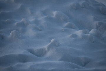 snow landscape made from mounds of snow and snow drifts sunlight causing shadows and shapes that look like faces in the freshly fallen snow on a cold winters day background for horizontal format