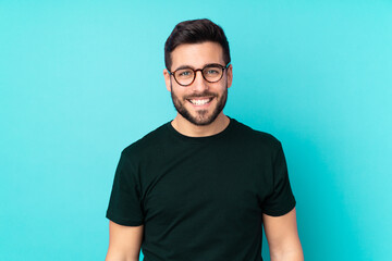 Caucasian handsome man isolated on blue background with glasses and happy