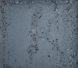 close up of textured cement wall damaged by weather old and weathered with small pebbles revealed cracks and crevices grungy looking dark grey for background effect for construction or industrial look