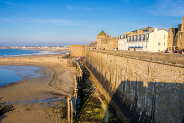 Saint-Malo, France - August 25, 2019: Beach in the evening sun and Historic wall of the old city of Saint-Malo, Brittany on the English Channel coast