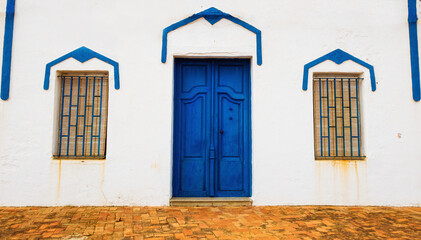 Fototapeta na wymiar Facade of a white house, with a beautiful blue door, and some windows with iron wrought iron bars and some beautiful blue frames, in a Mediterranean style.