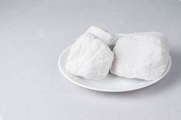 Large crystals of sodium chloride- food salt on a white plate. Food flavor enhancer. Organic NaCl natural minerals on light background. Copy space