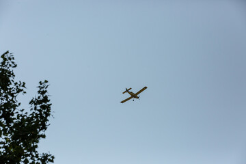 Small airplane silhouette against blue summer sky