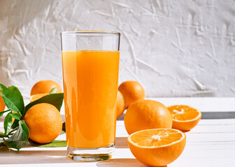 Ripe bio oranges and a glass of fresh squeezed orange juice on white wooden background. Organic Sicilian oranges.