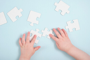 childrens hands holding puzzles on a blue background