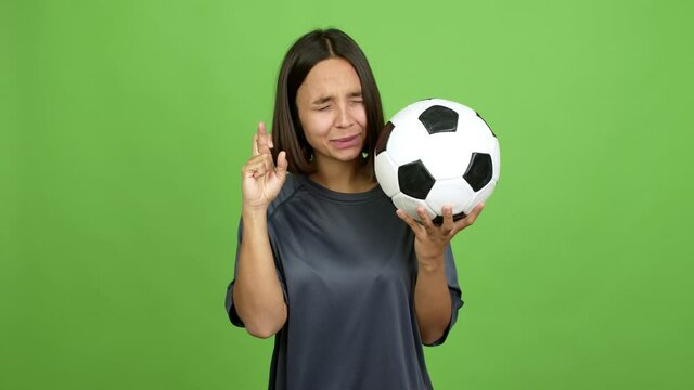 Young brunette woman playing futbol with fingers crossing over isolated background. green screen chroma key