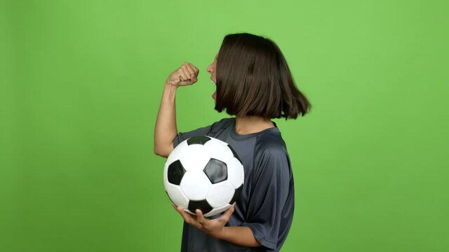 Young brunette woman playing futbol and celebrating a victory over isolated background. green screen chroma key