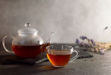 a teapot and a cup of tea, the teapot stands on a basalt stand