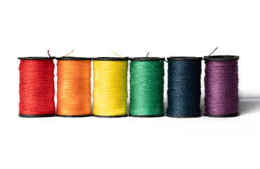 Spools of thread in colors of the rainbow on white background