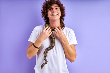 smiling guy stand brave with snake on him, caucasian male doesn't afraid of animals