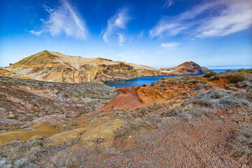 Rocks and multicolored ocher sands, blue sea at the eastern point of the island of Madeira and the...