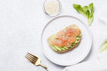 Bran bread toast with salmon and avocado on white stone table background. Flat lay, top view, copy space