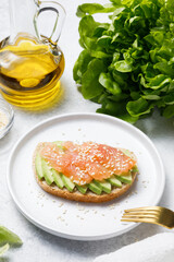 Bran bread toast with salmon and avocado on white stone table background.
