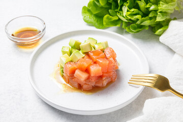 Salmon avocado tartare on white stone table background. Close up
