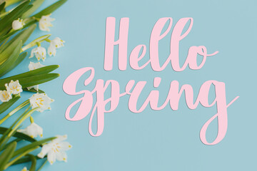 Hello spring floral greeting card, handwritten greetings on white spring flowers border on blue background. Spring time. Stylish floral  card, handwritten greetings © sonyachny
