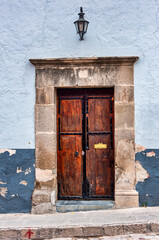 A vintage reinforced wooden door with a stone frame and a blue wall