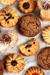 Different types of shortcrust pastry cookies: with chocolate, jam, sesame seeds, oatmeal. Assorted cookies on a light background, top view