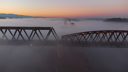 Bridge at Sunrise with a red sky in the Horizon . The picture was taken by a drone. the River unter the Bridge called Rhein.  scary fog is around the bridge.