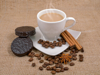 coffee and milk, cinnamon, anise and biscuits on a background sacking