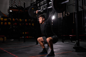 Fitness man doing aweight training by lifting barbell. Young athlete training alone. Bodybuilder...