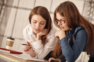 Close up Two Happy Young Businesswomen at the Office Talking About Business Report on Paper.