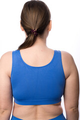 A young plus size woman in a sports uniform prepares for a home workout and stands with her back to the camera. Warm up before training. White background.