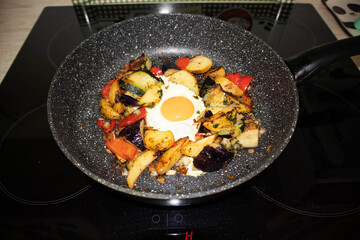Serve one fried egg with baked vegetables, sausage. Round bright yellow yolk in the center.