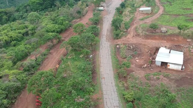 Panning up to the building facing Calandula waterfalls in Angola, road, and hills leading to the waterfall in the distance.  Aerial