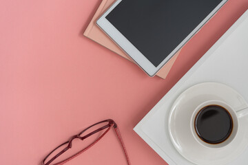 cup of coffee on a table with  lap top and glasses on pink background