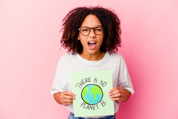Young african american mixed race woman holding a world protection concept cardboard screaming very angry and aggressive.