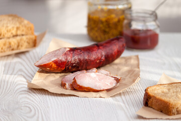 Sliced smoked sausage in a wooden table with bread and ketchup.