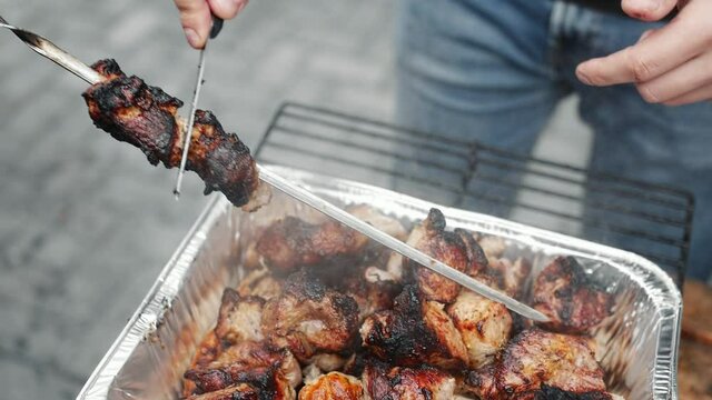 Man takes a kebab off a skewer.