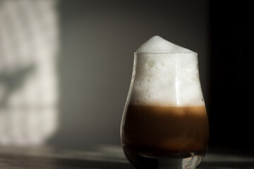 Glass with milky coffee latte or cappuccino in the morning. Sunlight, good day concept.