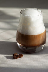 Glass with milky coffee latte or cappuccino in the morning. Sunlight, good day concept.