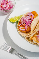Dish of fish and shrimp tacos with flaked onion