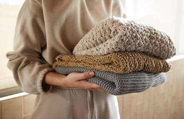 Woman hand holding a stack of sustainable organic cloths in tracksuit at home, eco friendly fabric