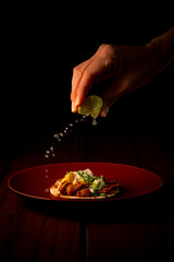 Tasty taco al pastor on red plate squeezing lemon