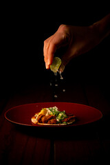 Tasty taco al pastor on red plate squeezing lemon