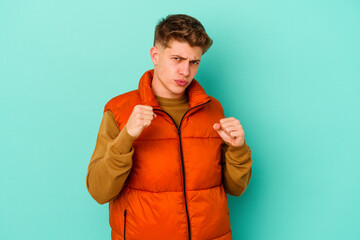 Young caucasian man isolated on blue background showing fist to camera, aggressive facial...